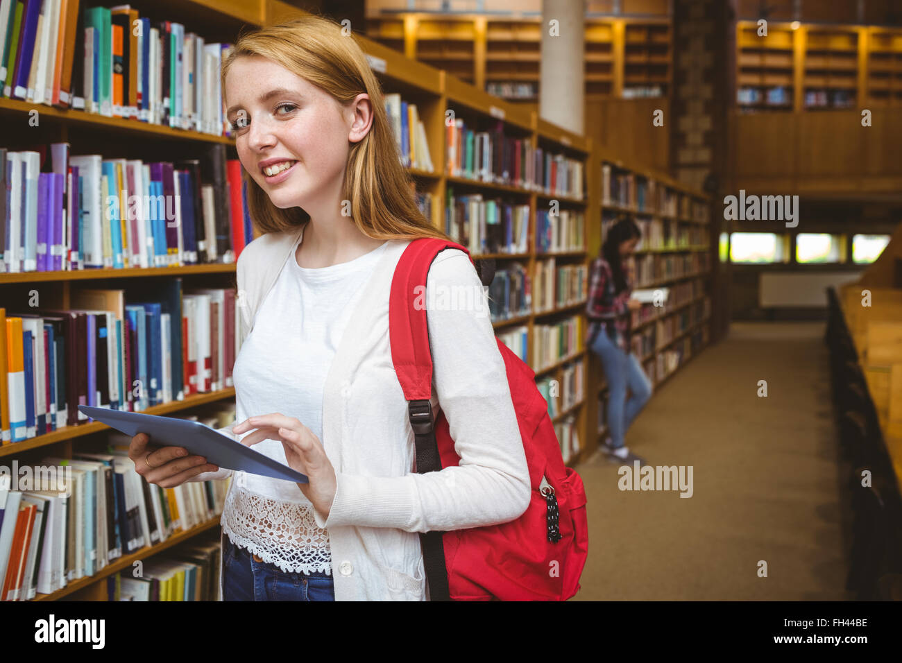 Studente sorridente con zaino utilizzando tablet in libreria Foto Stock