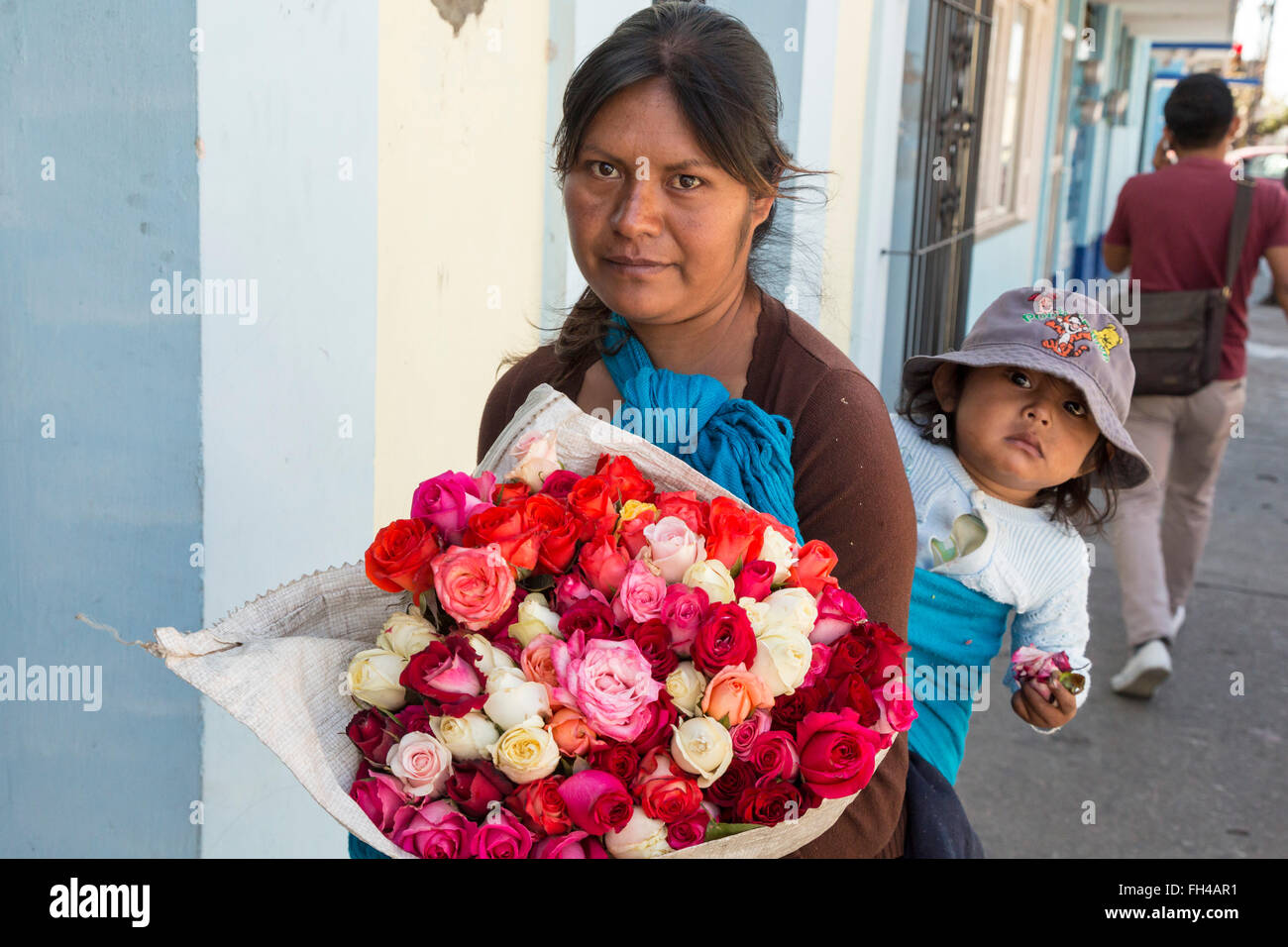 Oaxaca, Messico - una giovane donna che porta il suo bambino vende fiori sulla strada. Foto Stock