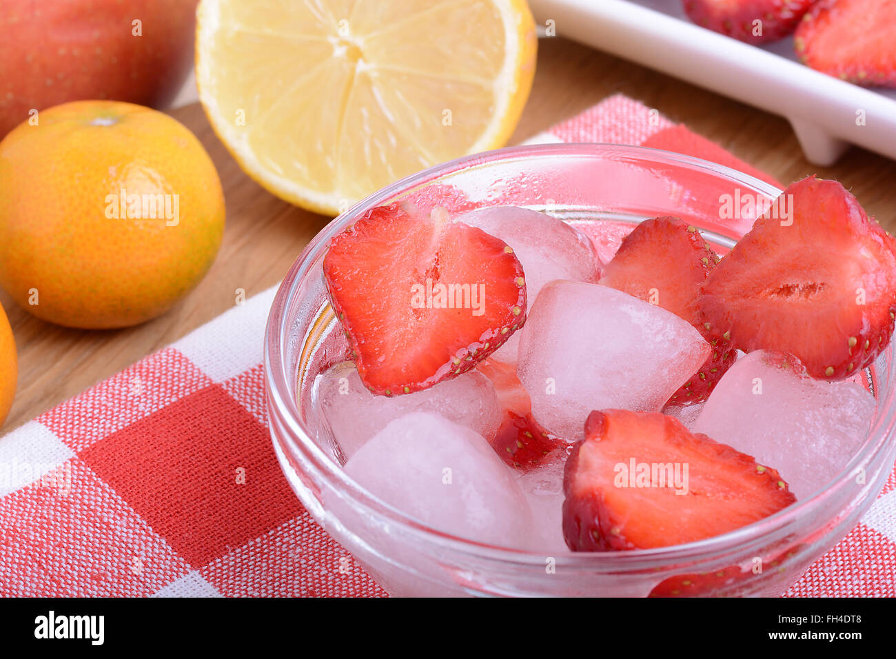 Una fetta di fragola rossa sulla lastra di vetro con il limone ed il mandarino in party tema sfondo Foto Stock