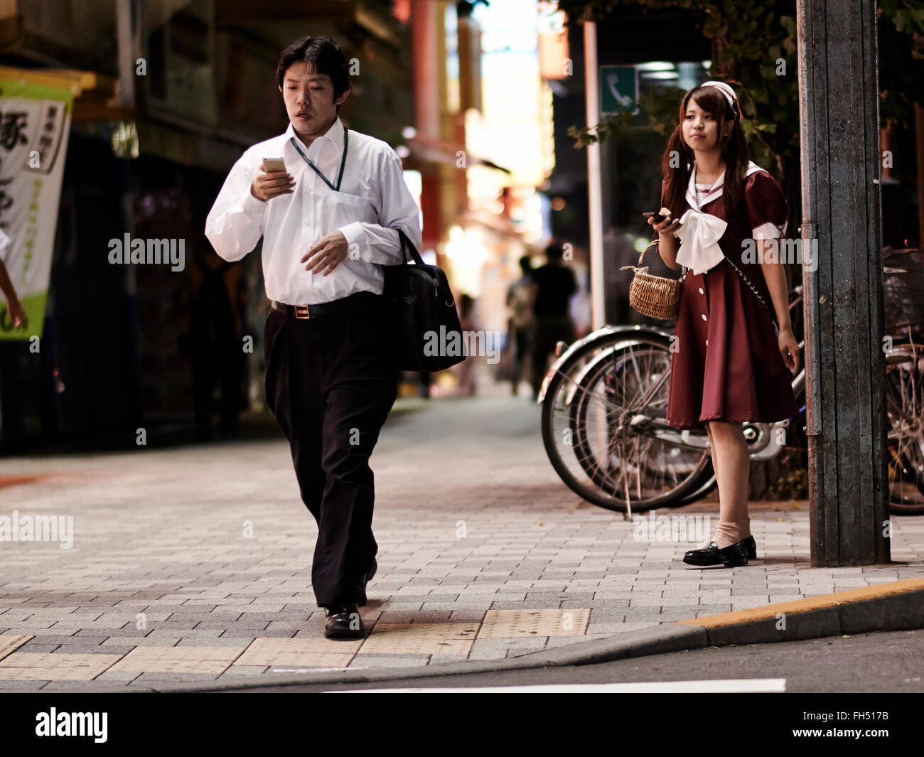 Donna Uomo sbirciare dietro in una strada a Tokyo Foto Stock