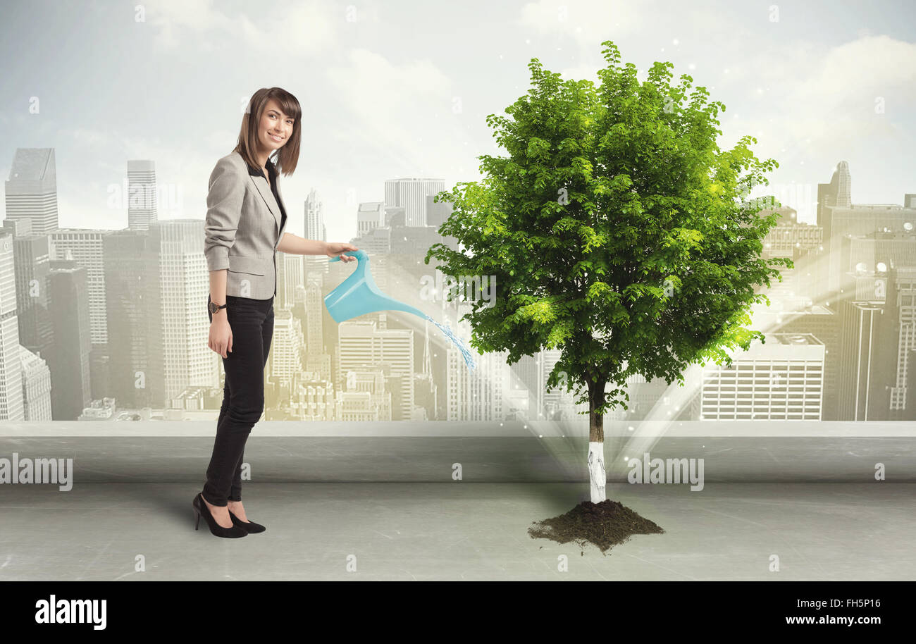 Imprenditrice di irrigazione albero verde su sfondo della città Foto Stock