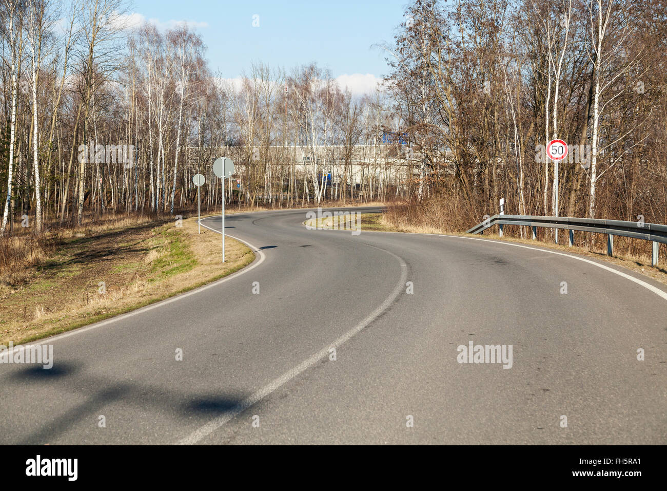 Strada con una 'S' curva e il segnale di limite di velocità Foto Stock