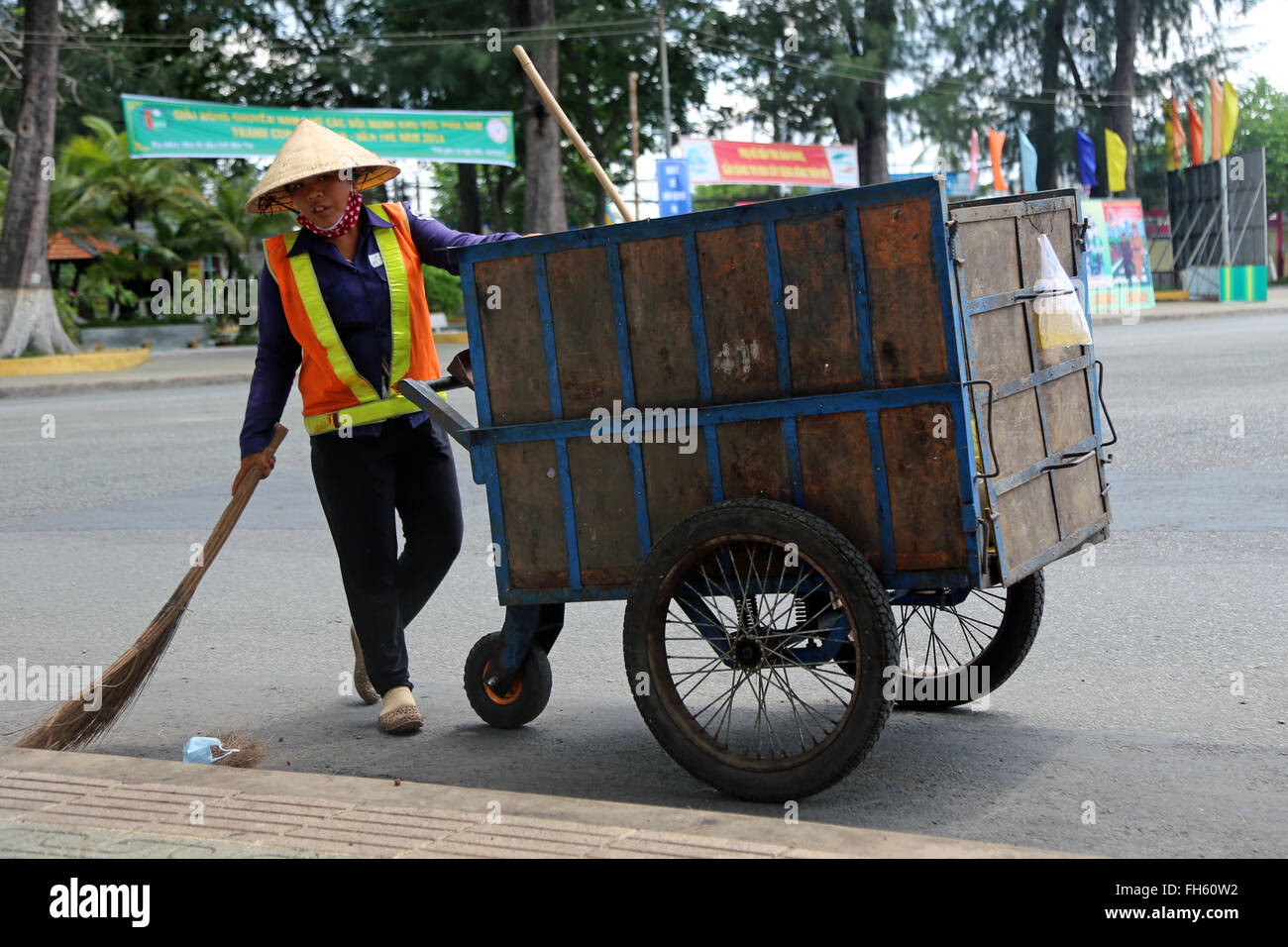 Ben tre, Vietnam: una donna spazza le strade su una strada principale Foto Stock