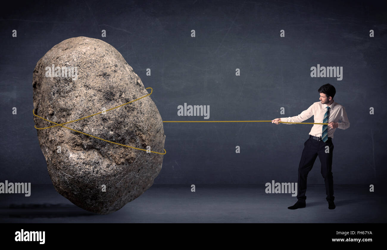 Imprenditore tirando enorme roccia con una corda Foto Stock