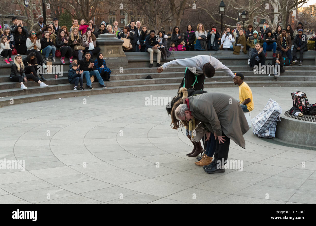 Street performance in Washington Square Park di acrobat somersaulting su volontari con la folla di spettatori Foto Stock