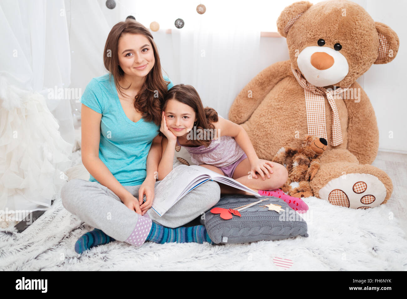 Ritratto di due belle sorelle sorridente seduto in camera per bambini insieme Foto Stock