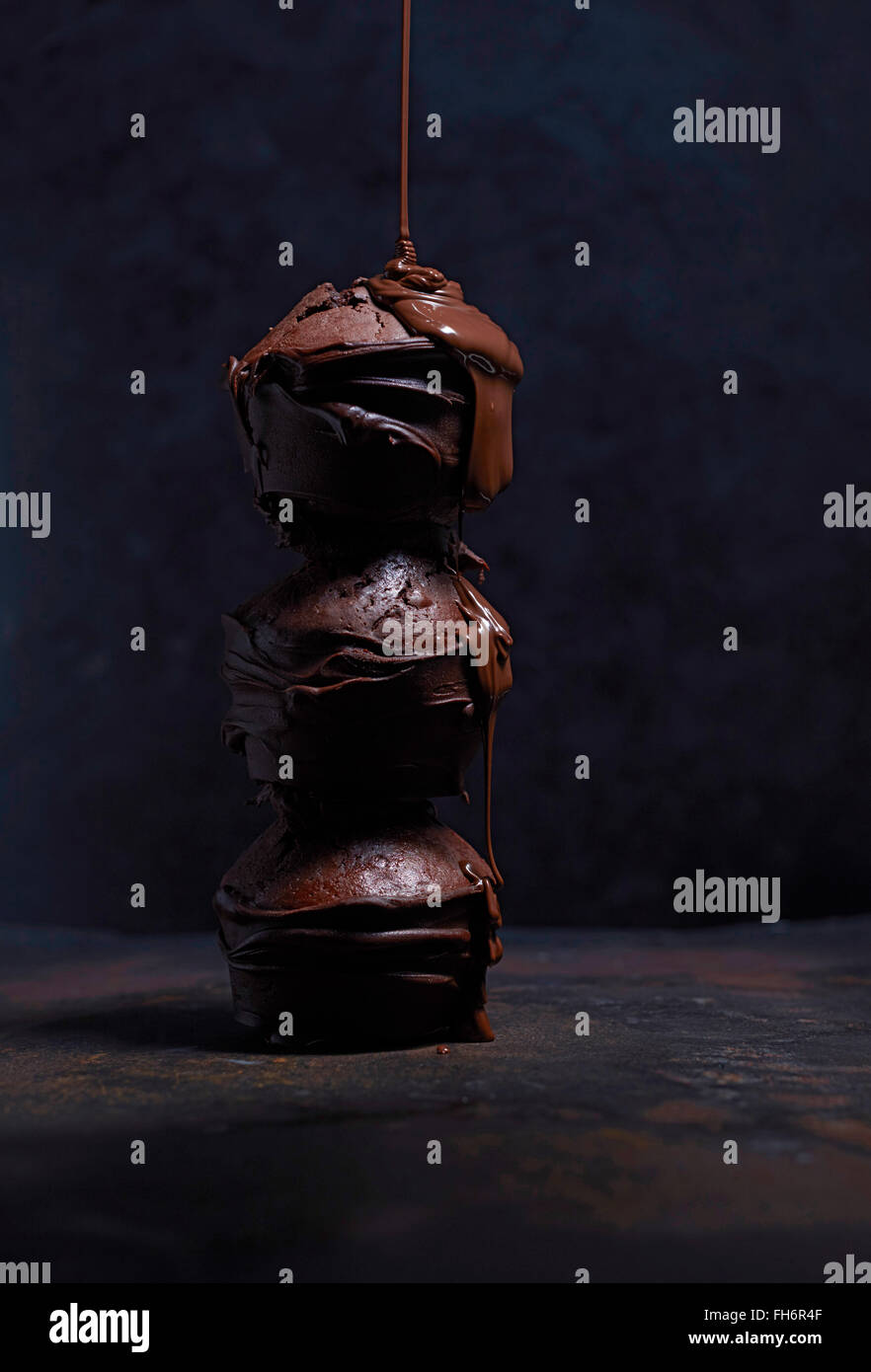 Il liquido di gocciolamento di cioccolato sulla pila di tre muffin al cioccolato Foto Stock