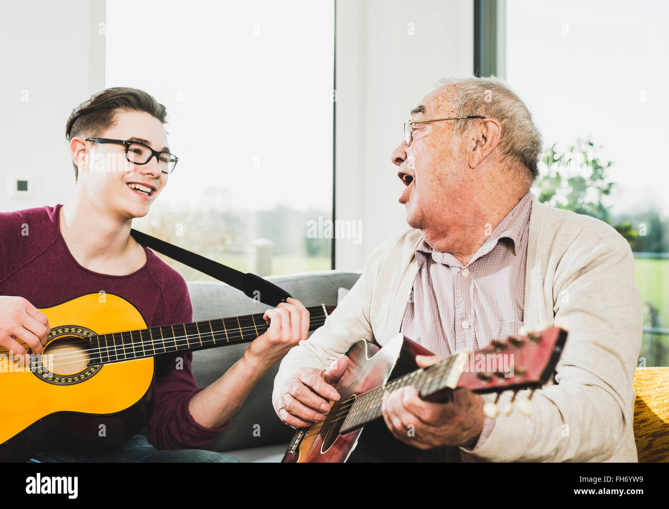 Uomo senior di cantare e suonare la chitarra con il suo nipote Foto Stock