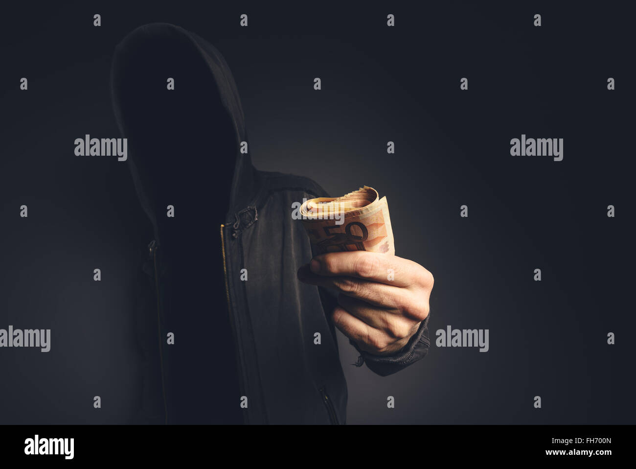 Irriconoscibile incappucciati hacker offrendo denaro contante, cyber criminalità, ricatto e estorsione concetto. Foto Stock