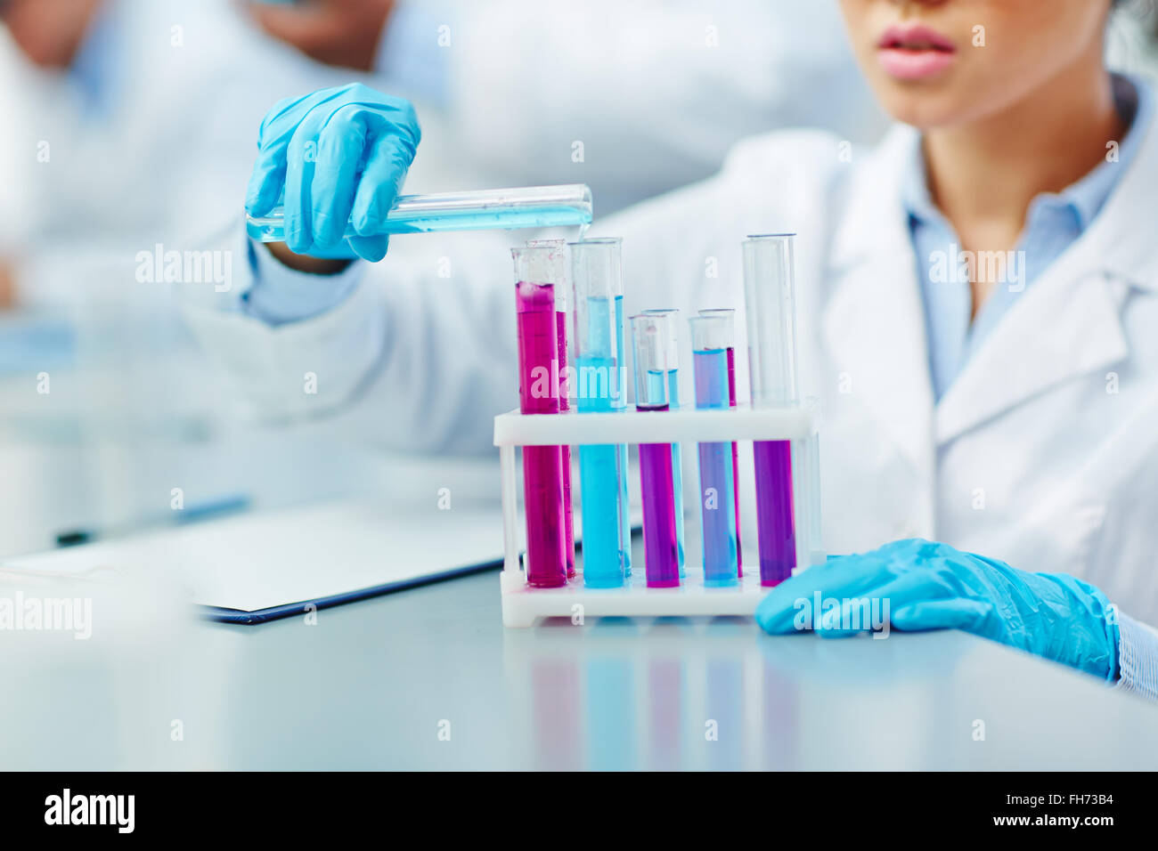 Giovane donna lavora con sostanze chimiche in laboratorio scientifico Foto Stock