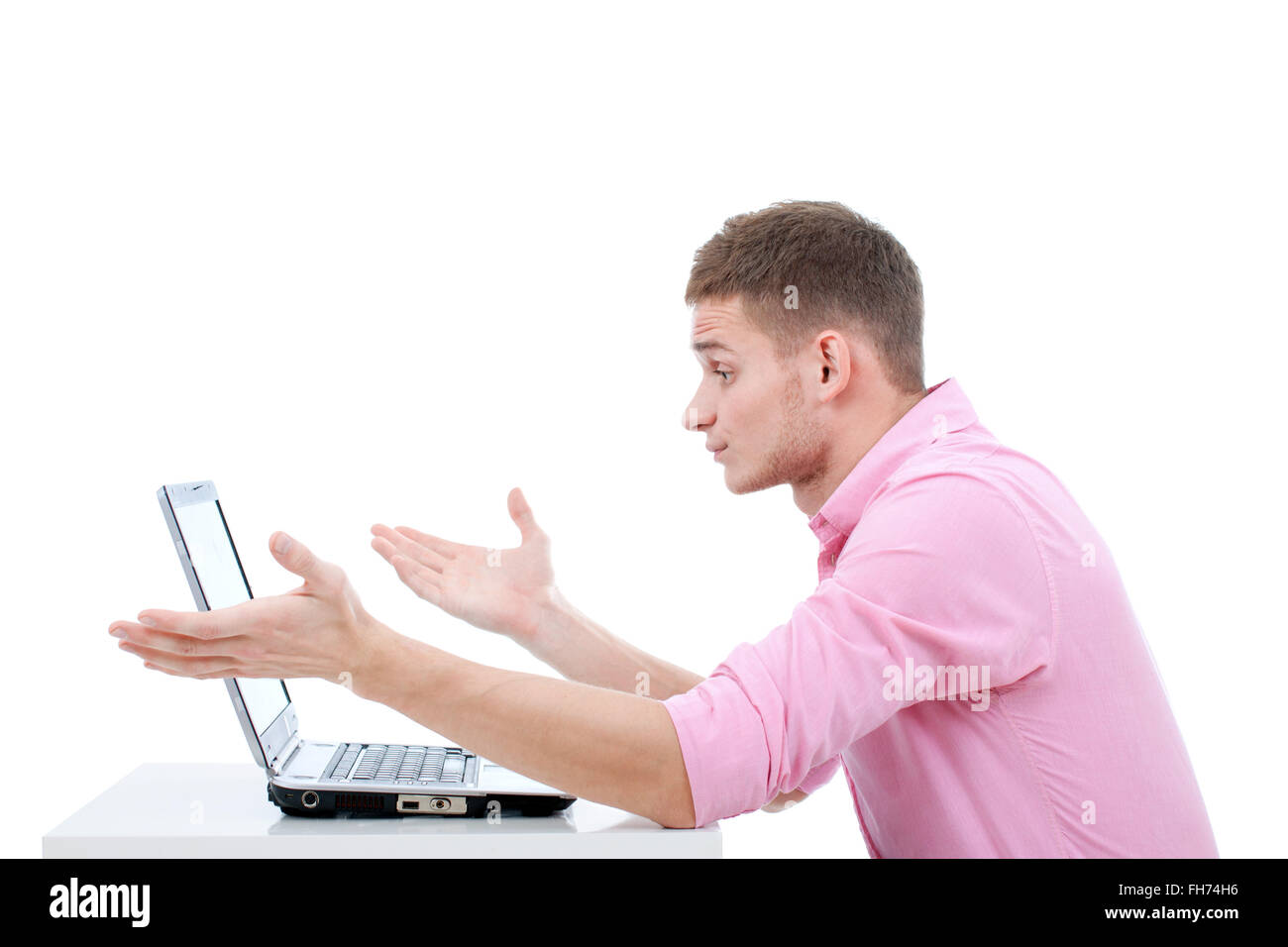 Un giovane uomo bello sedersi al tavolo e lavorare sul suo computer portatile. Qualcosa è andato storto e che egli esprime profonda pertrubation Foto Stock