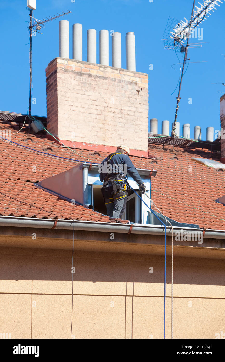 Lavoratore di manutenzione con la fascetta di sicurezza su un tetto di casa Foto Stock