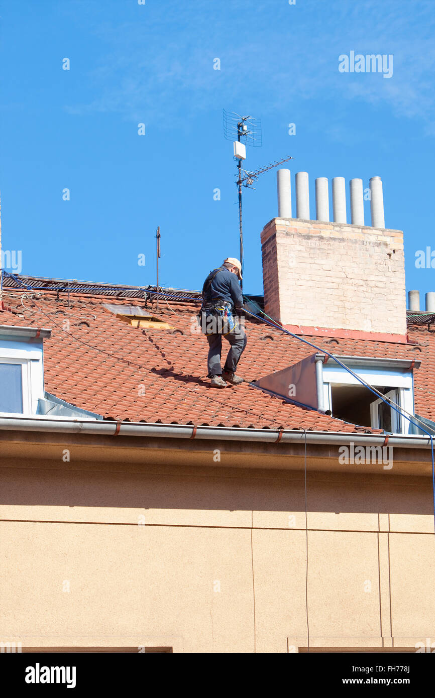 Lavoratore di manutenzione con la fascetta di sicurezza su un tetto di casa Foto Stock