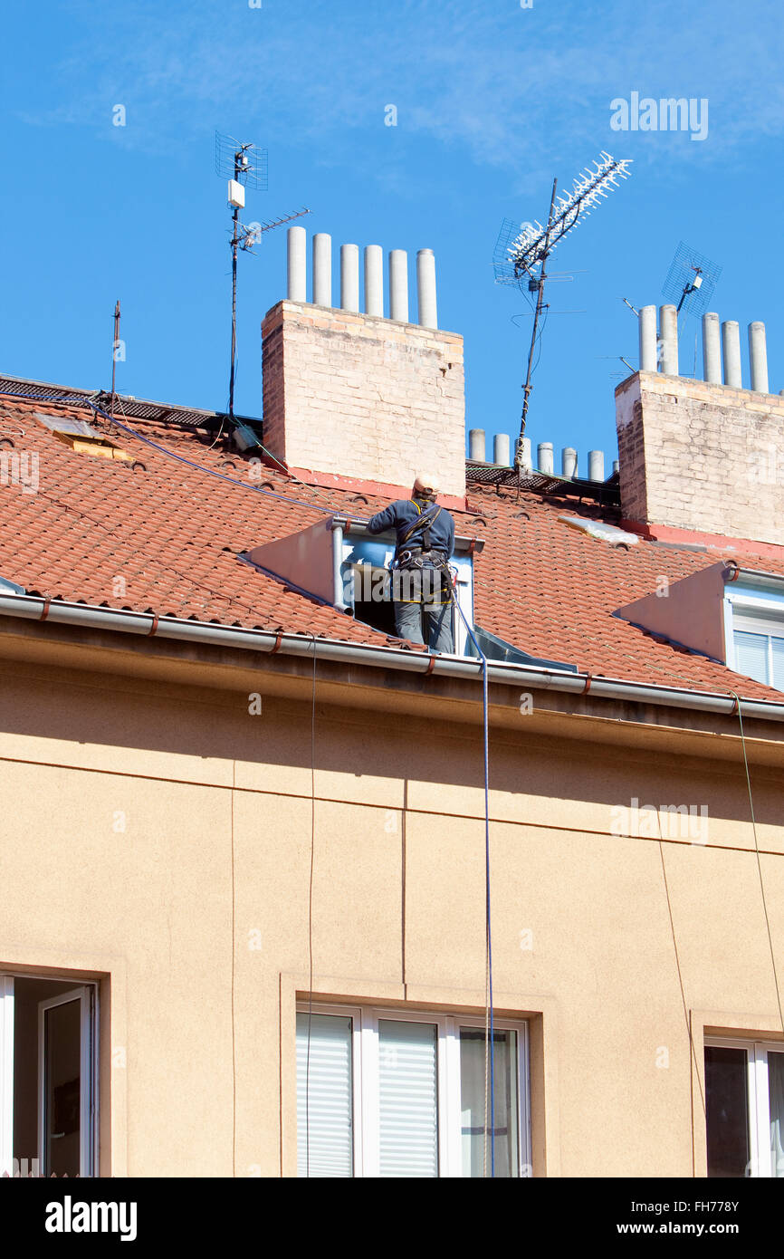 Lavoratore di manutenzione con la fascetta di sicurezza su un tetto di casa Foto Stock