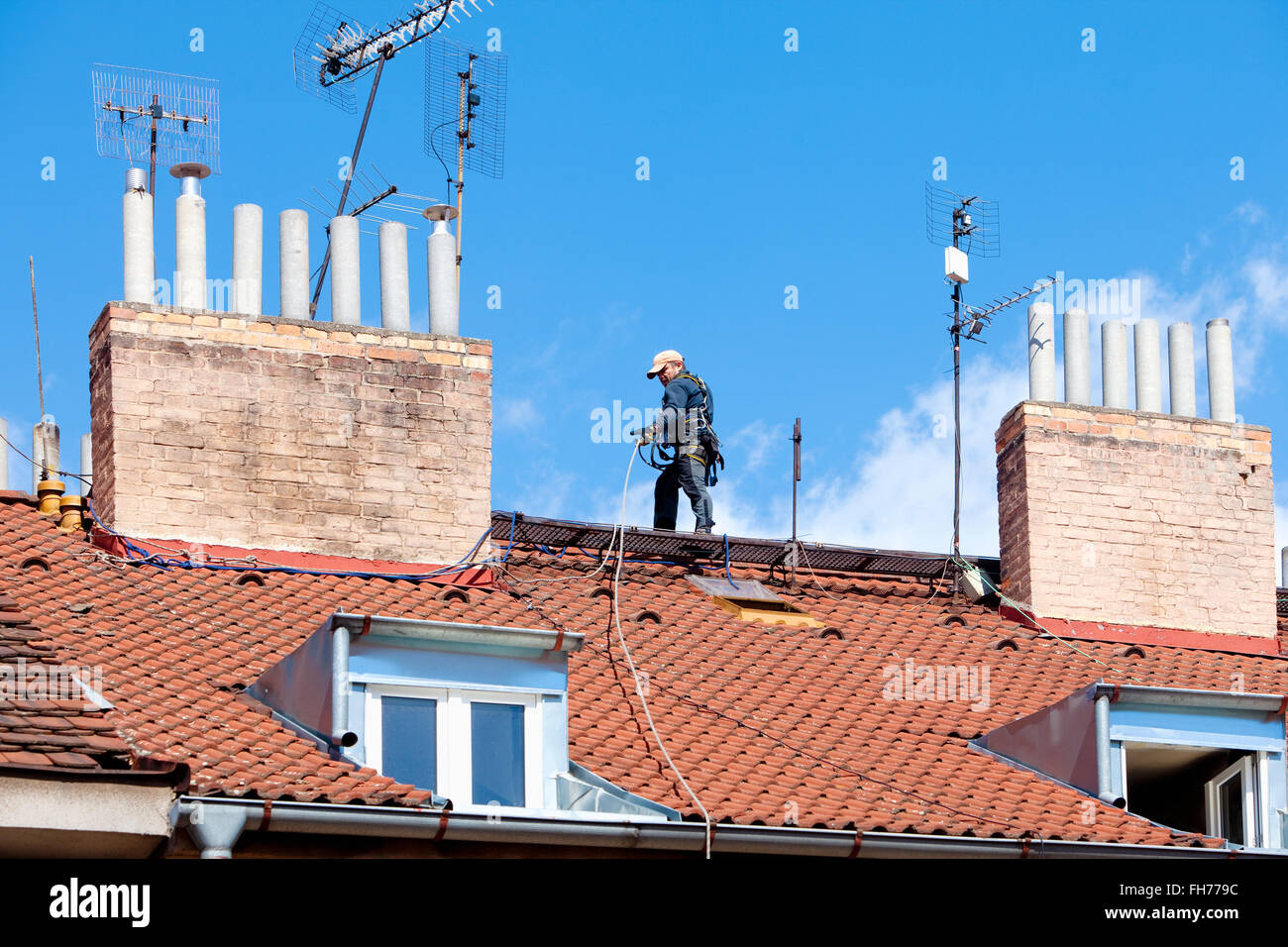 Lavoratore di manutenzione con la fascetta di sicurezza su un tetto di casa Foto Stock