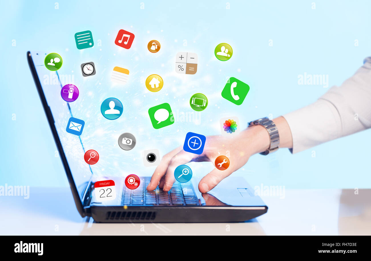 Mano, premendo il laptop moderno con mobile app icone e simboli Foto Stock