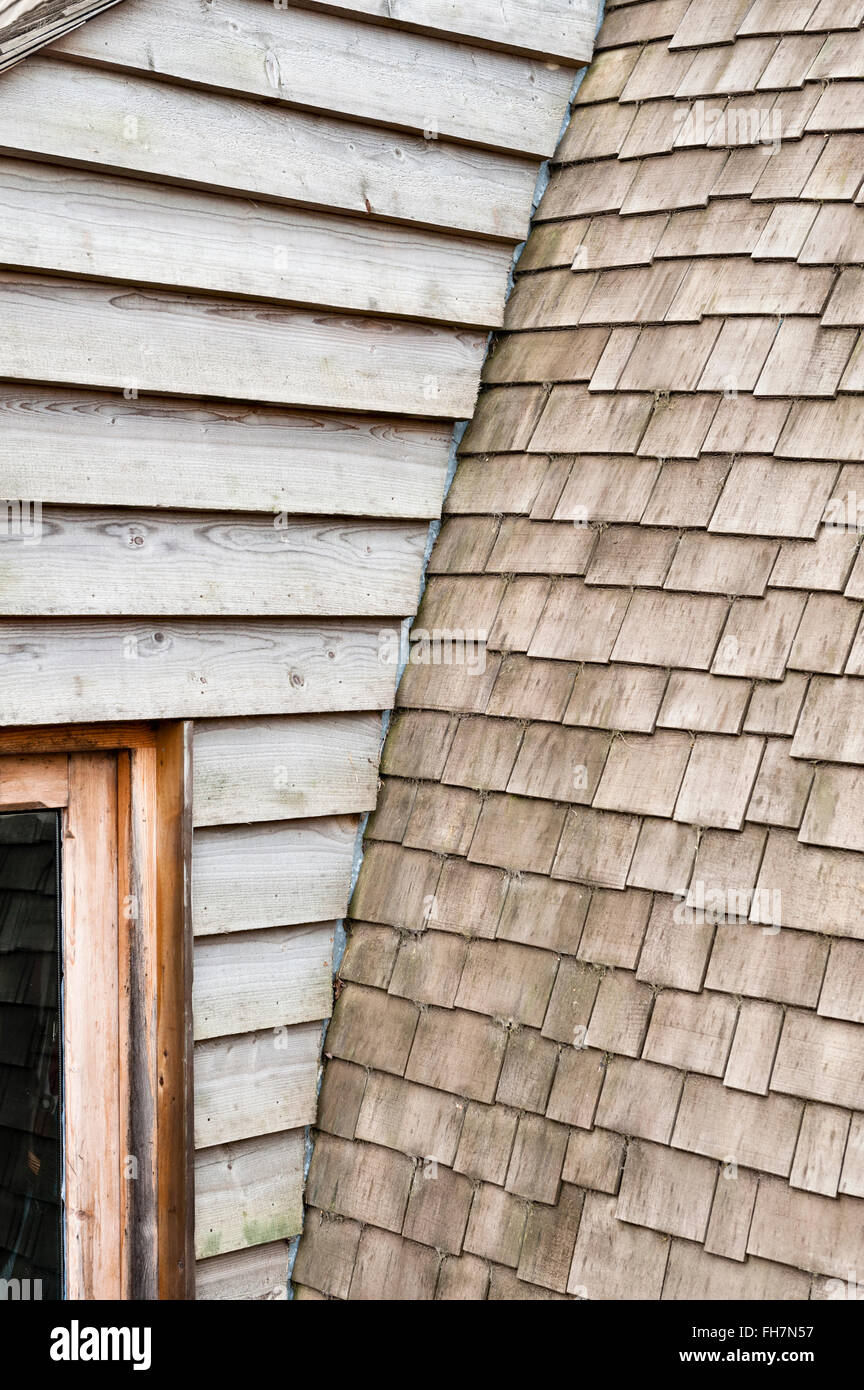 Herefordshire, Regno Unito. Un dettaglio di un auto costruita casa, rivestita di legno con un tetto curvo con coperta in legno Scandole di cedro Foto Stock