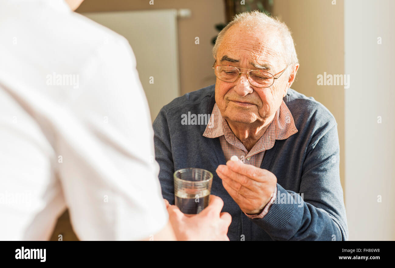 Senior man getting tablet e bicchiere di acqua Foto Stock
