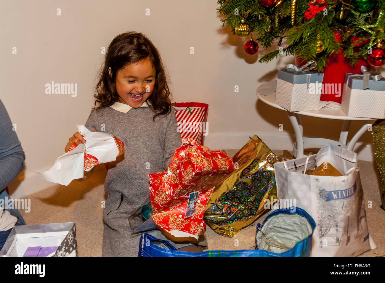 Una razza mista bambino aprendo i suoi regali di Natale Il giorno di Natale, Brighton, Sussex, Regno Unito Foto Stock
