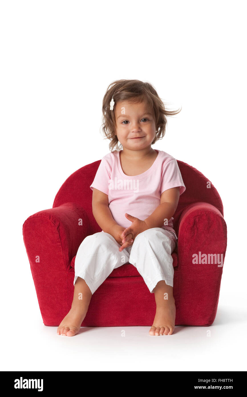 Il Toddler ragazza seduta in una poltrona su sfondo bianco Foto Stock