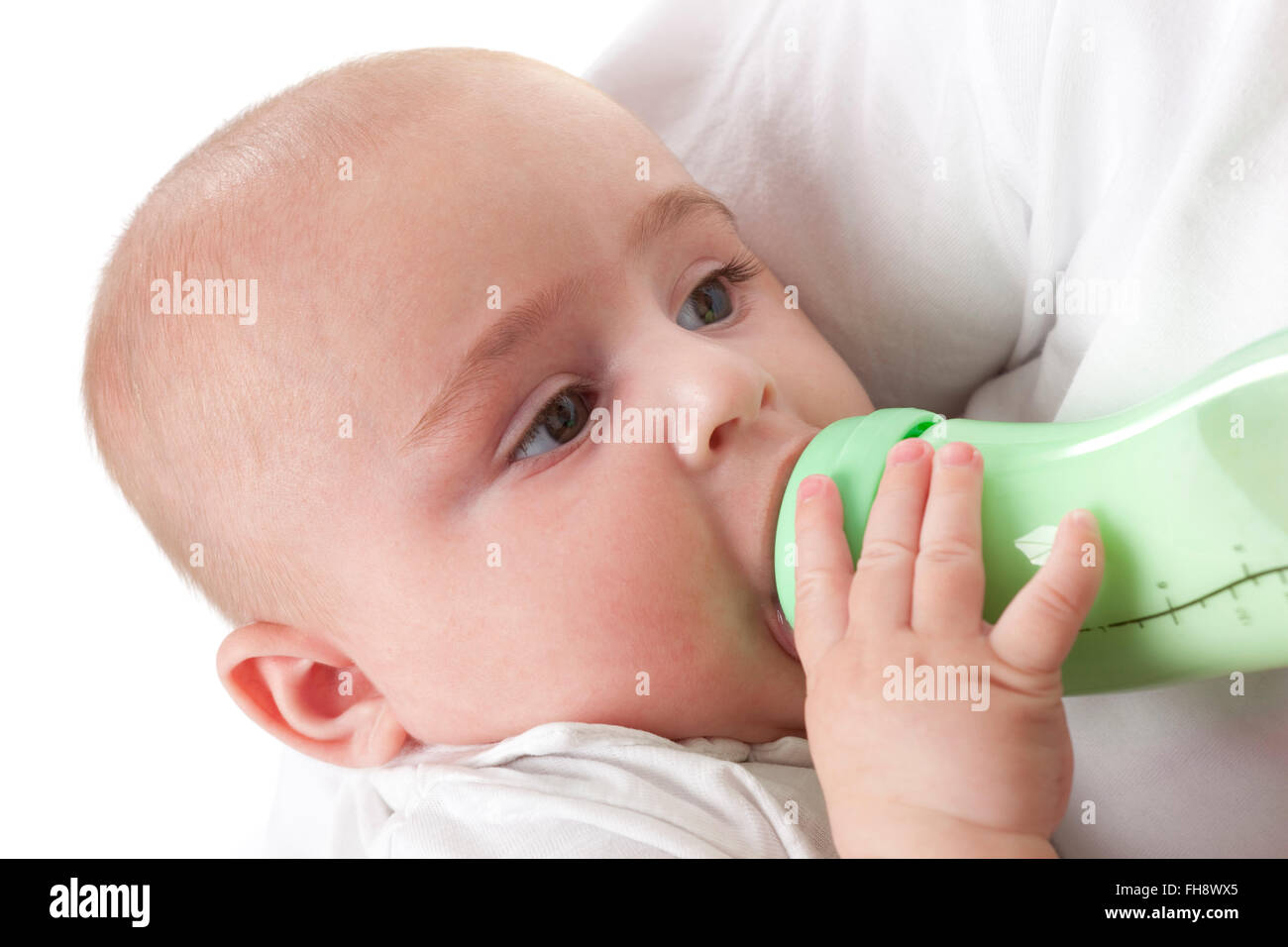 Bambino guardando i suoi genitori mentre si beve da un biberon su sfondo bianco Foto Stock