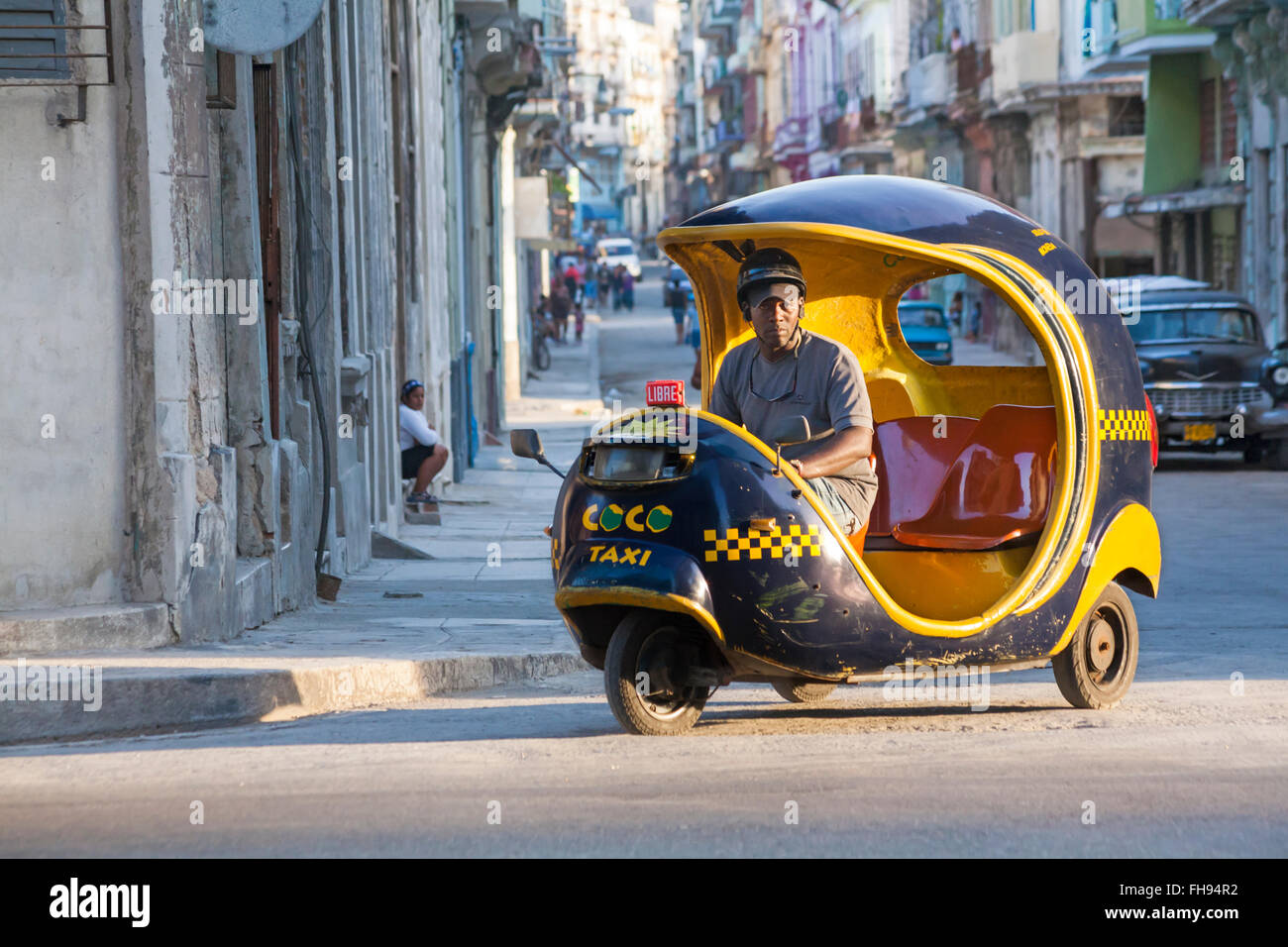 La vita quotidiana a Cuba - Locale uomo cocotaxi equitazione, coco taxi, giù street a l'Avana, Cuba, West Indies, dei Caraibi e America centrale Foto Stock