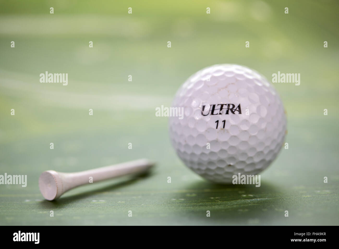 White pallina da golf e il raccordo a t su una foglia verde Foto Stock