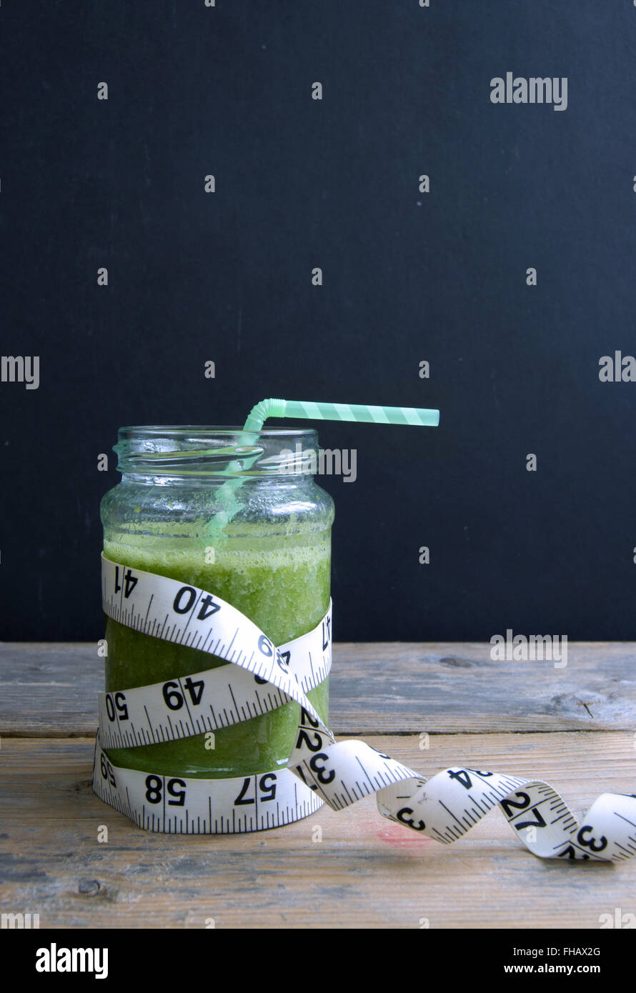 Un sano frullato verde con nastro di misurazione Foto Stock
