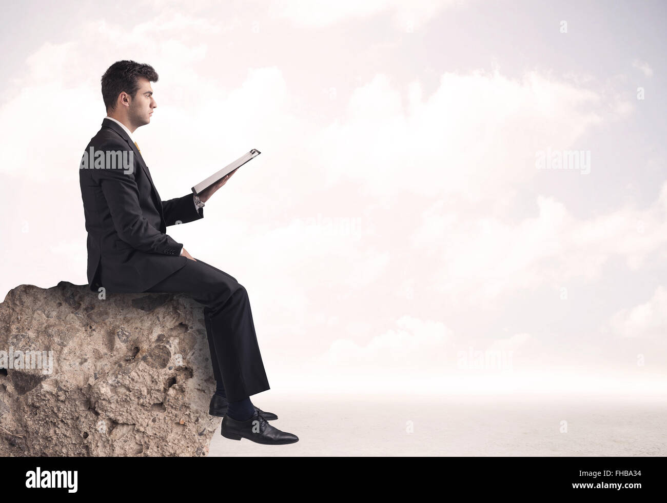Business uomo seduto sul bordo di pietra Foto Stock