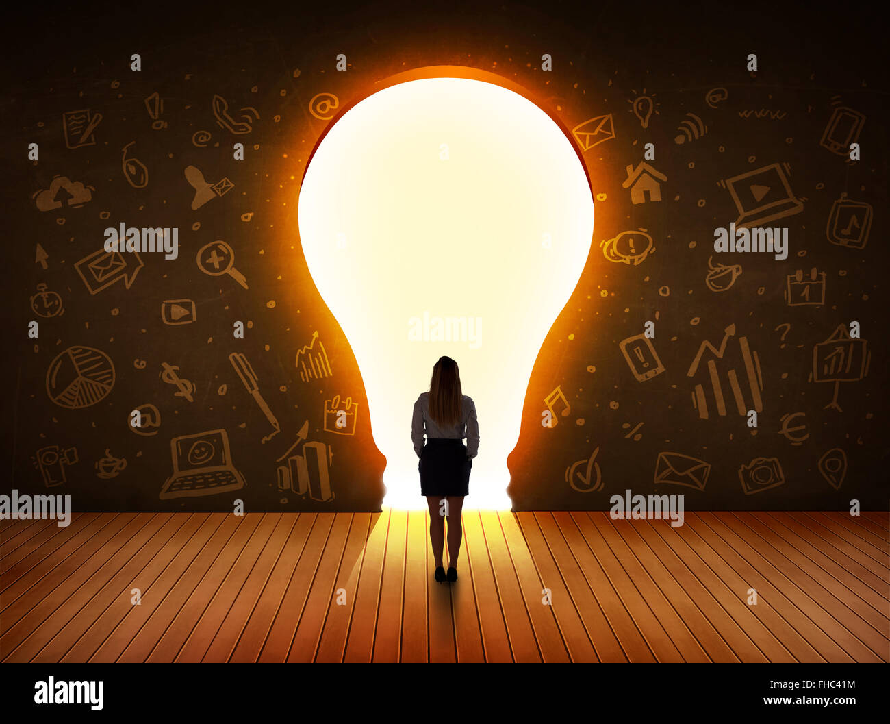 Business donna che guarda la luce brillante lampadina nella parete Foto Stock