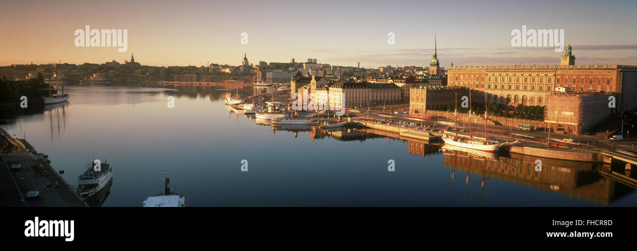 Barche ancorate lungo Skeppsbron all'alba con il Palazzo Reale e la Città Vecchia di Stoccolma Foto Stock