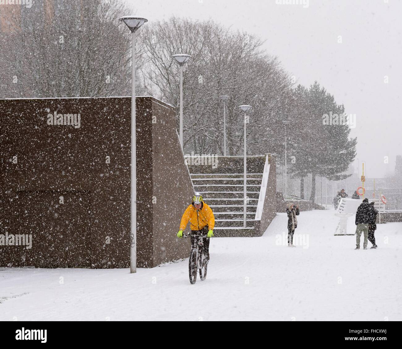 Un ciclista sfidando un giorno nevoso su Custom House quay marciapiede, Clyde Street, Glasgow, Scotland, Regno Unito Foto Stock