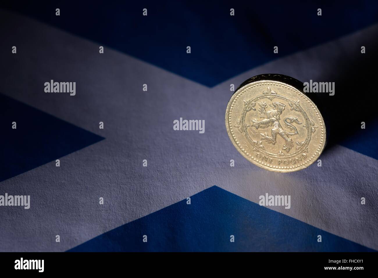 Uno scozzese pound coin che mostra leone rampante su una miniatura bandiera scozzese. Foto Stock