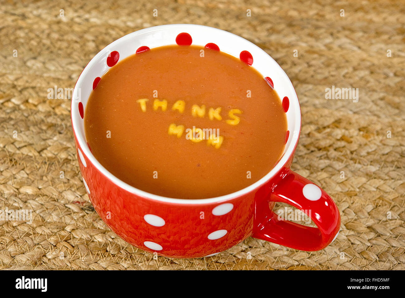 Messaggio in pasta a Mom galleggianti in zuppa di pomodoro in rosso e bianco polka dot zuppa mug. Foto Stock