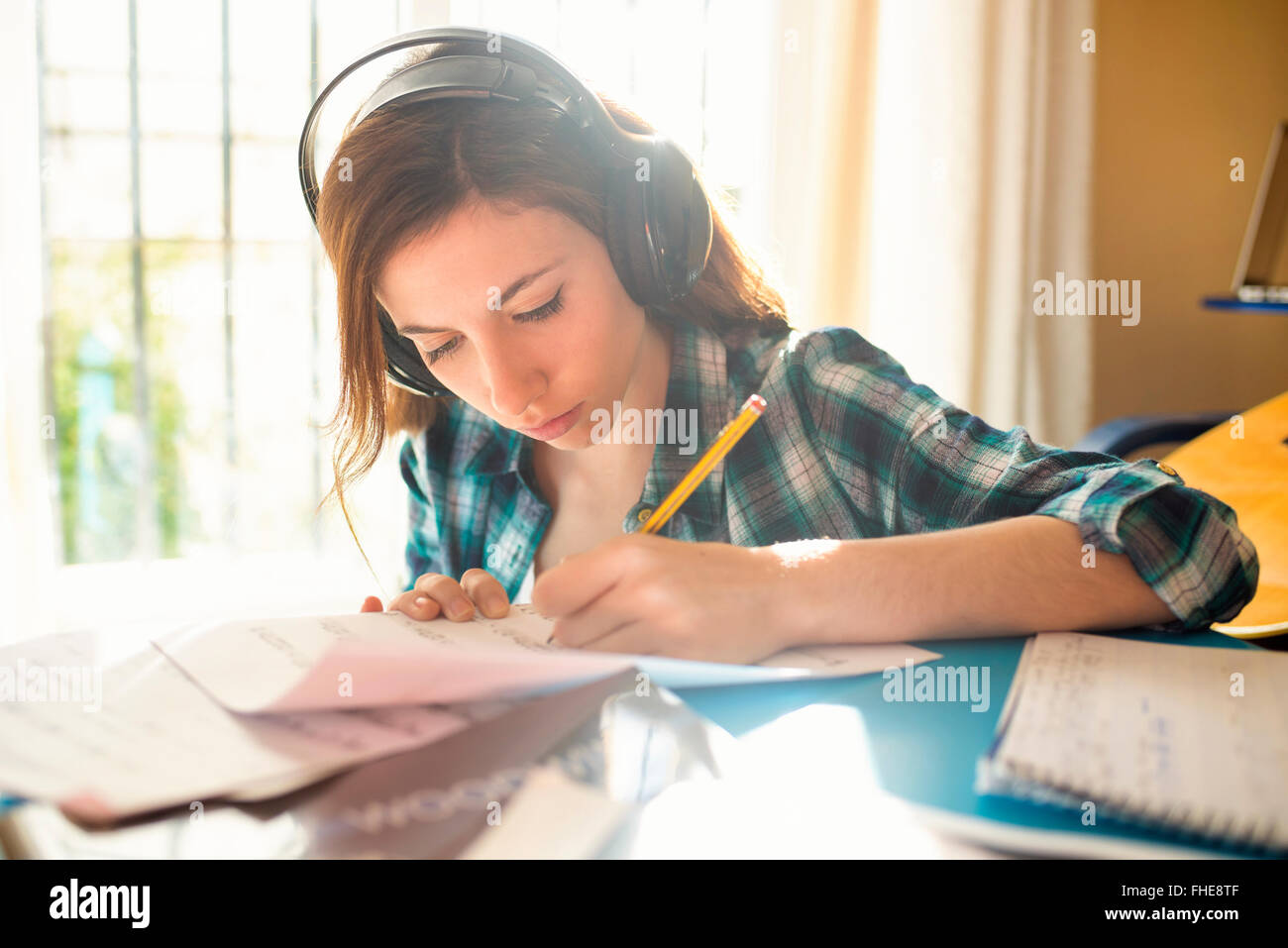 Giovane donna che indossa le cuffie la scrittura sul foglio di musica Foto Stock