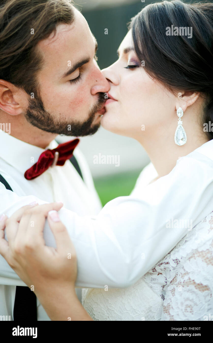 Sposa e lo sposo baciare. Coppie in viaggio di nozze, sposi novelli kiss. Chiudere ritratto. L'uomo in bow tie con bretelle. Foto Stock