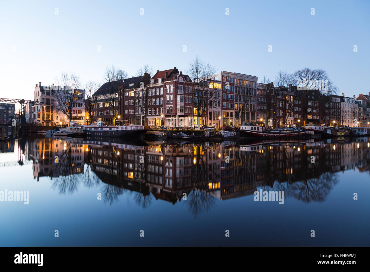Una vista lungo il canale Oudeschans ad Amsterdam al crepuscolo. Edificio, barche e riflessioni può essere visto. Vi è spazio per il testo Foto Stock