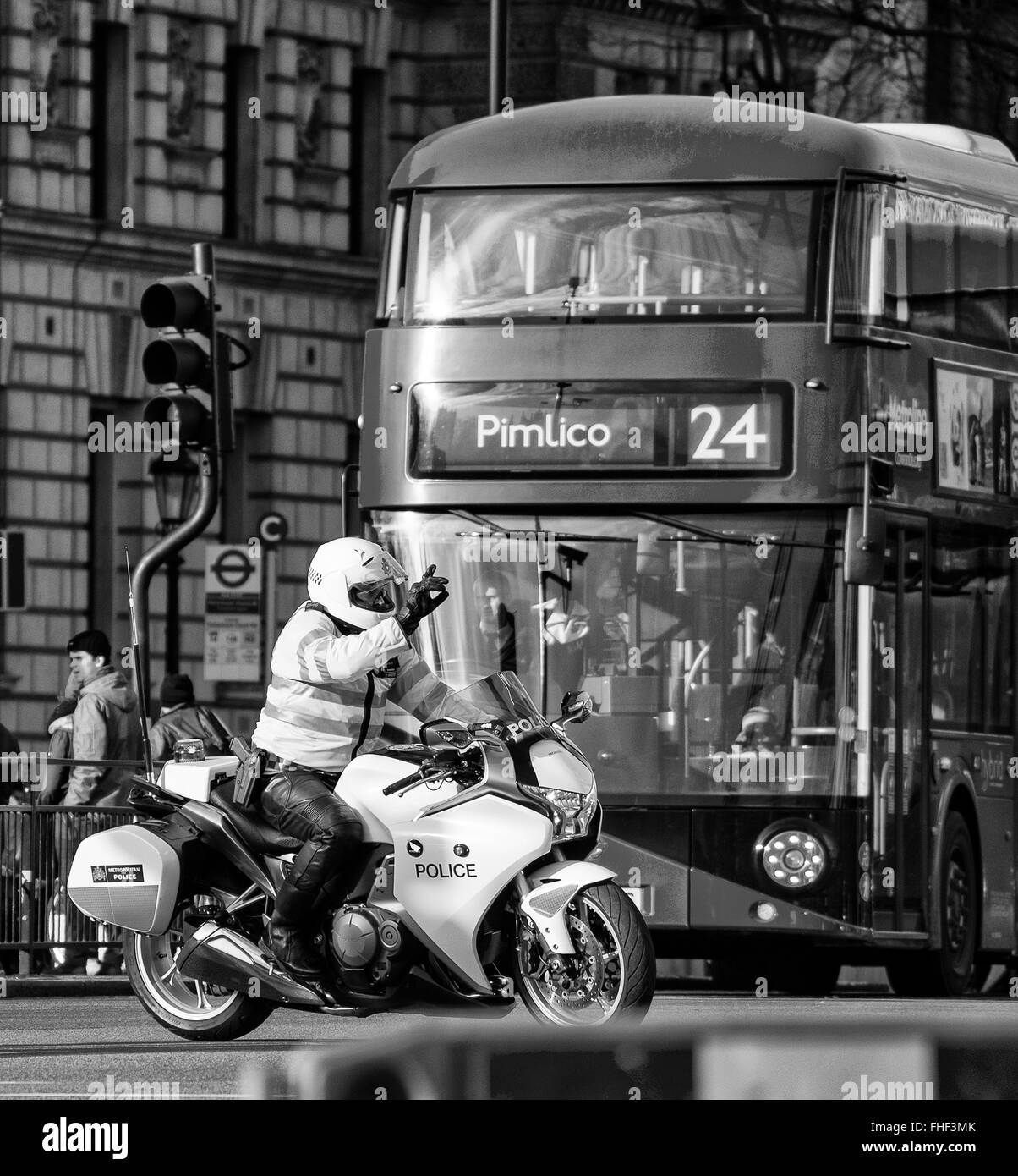 La Metropolitan Police motociclista tenendo alto il traffico in Whitehall con autobus numero 24 fino a Pimlico dietro Foto Stock
