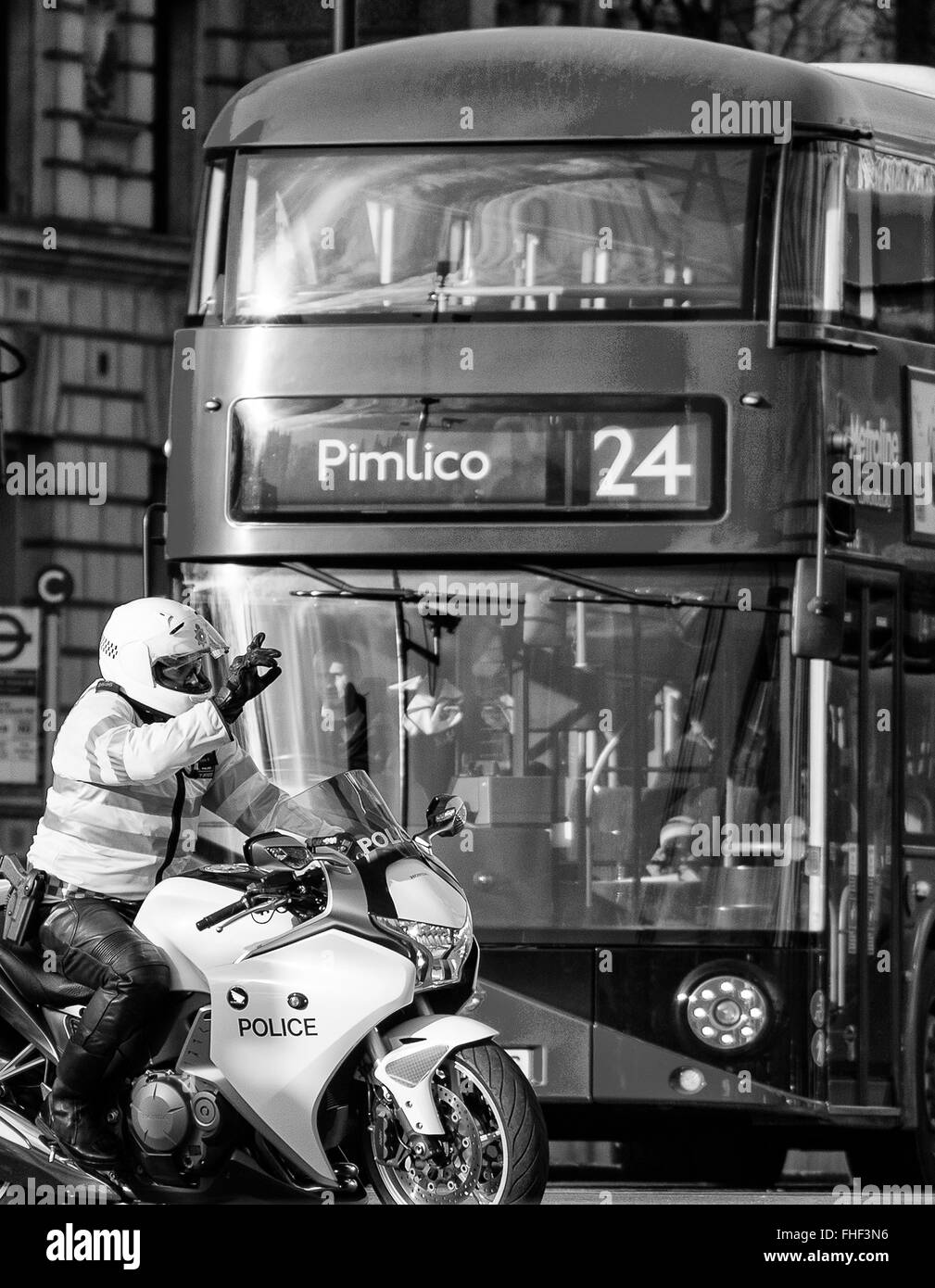 La Metropolitan Police motociclista tenendo alto il traffico in Whitehall con autobus numero 24 fino a Pimlico dietro Foto Stock