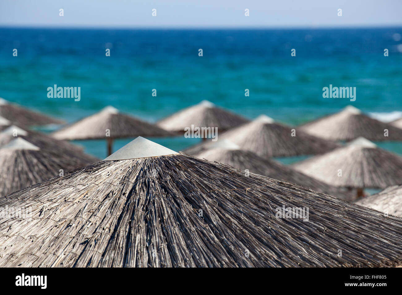 Più paglia ombrelloni da spiaggia, vista da sopra su un blu vedere sfondo. Foto Stock