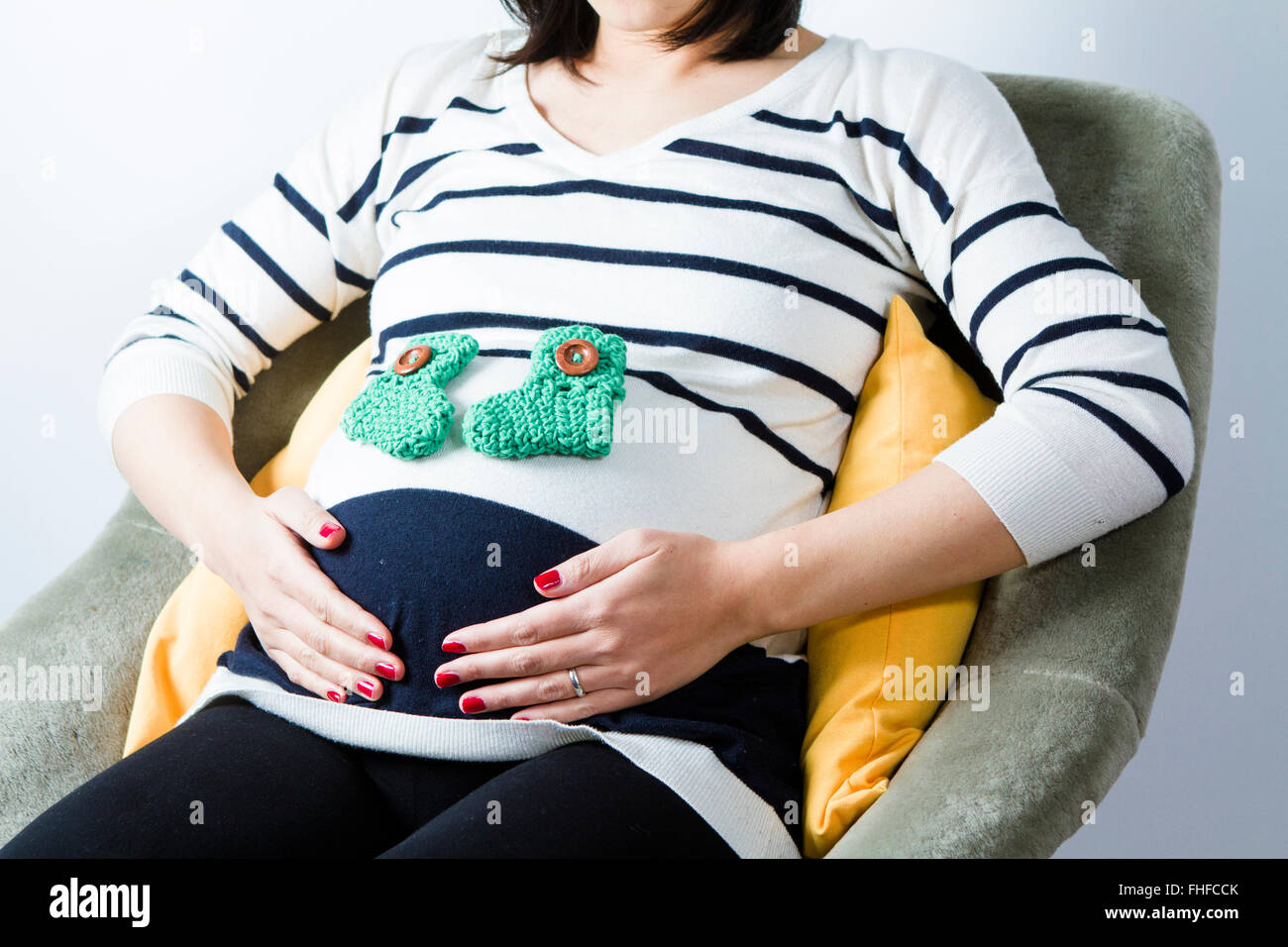 Donna incinta seduta con il bimbo di calze sulla pancia Foto stock - Alamy