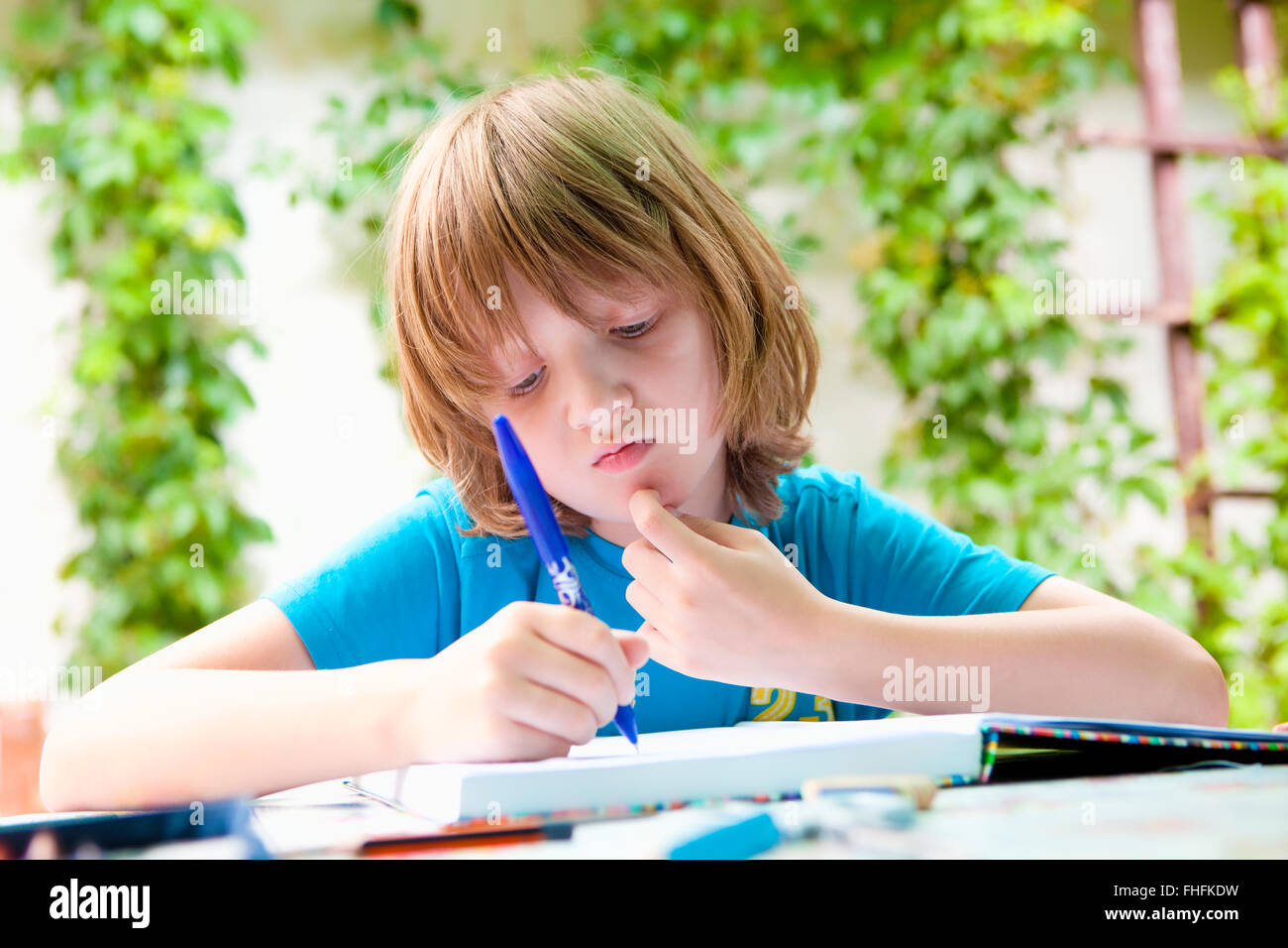 Ragazzo con capelli biondi Studiare all'aperto Foto Stock