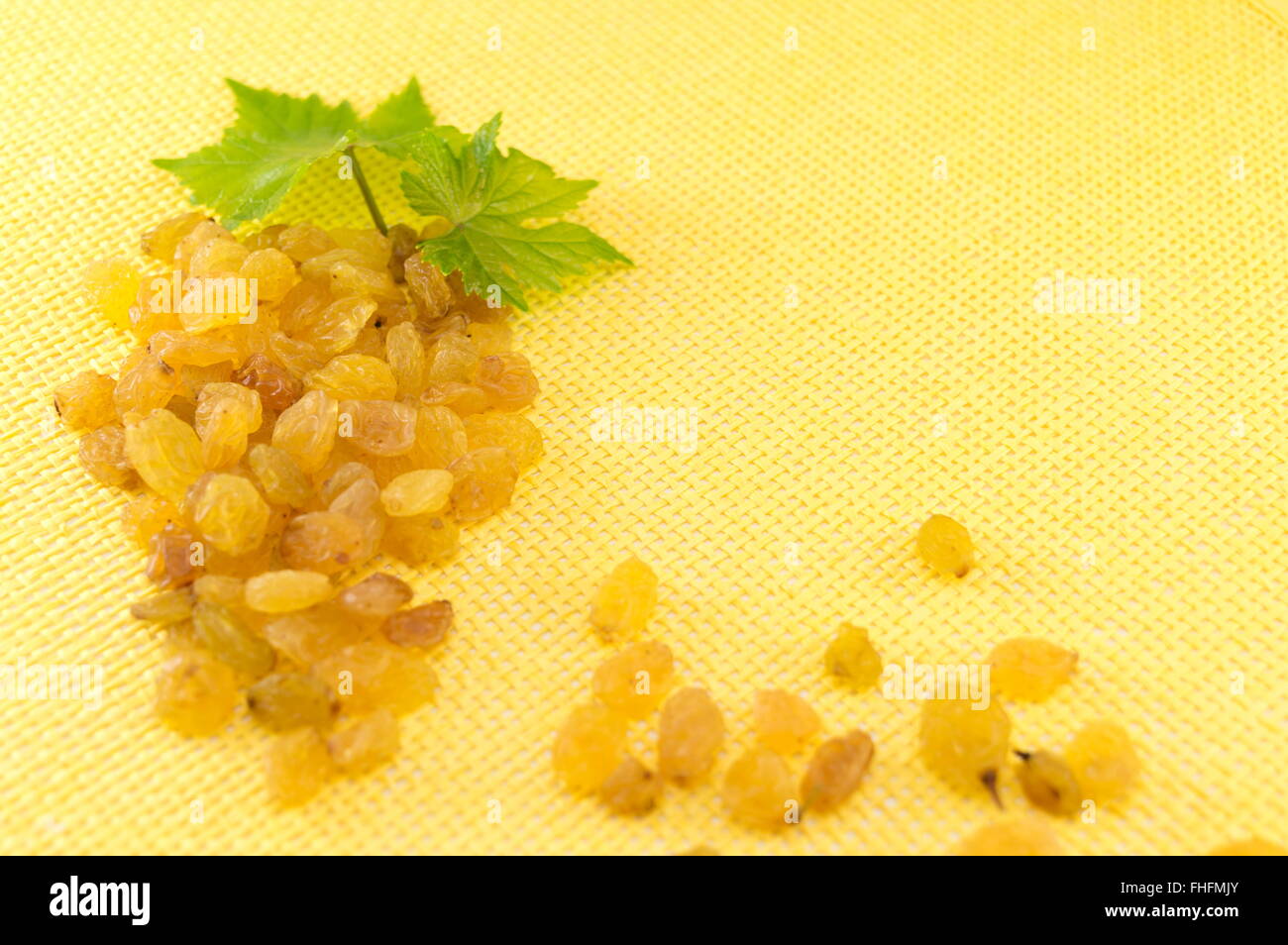 Uvetta formando un grappolo d'uva su sfondo giallo Foto Stock