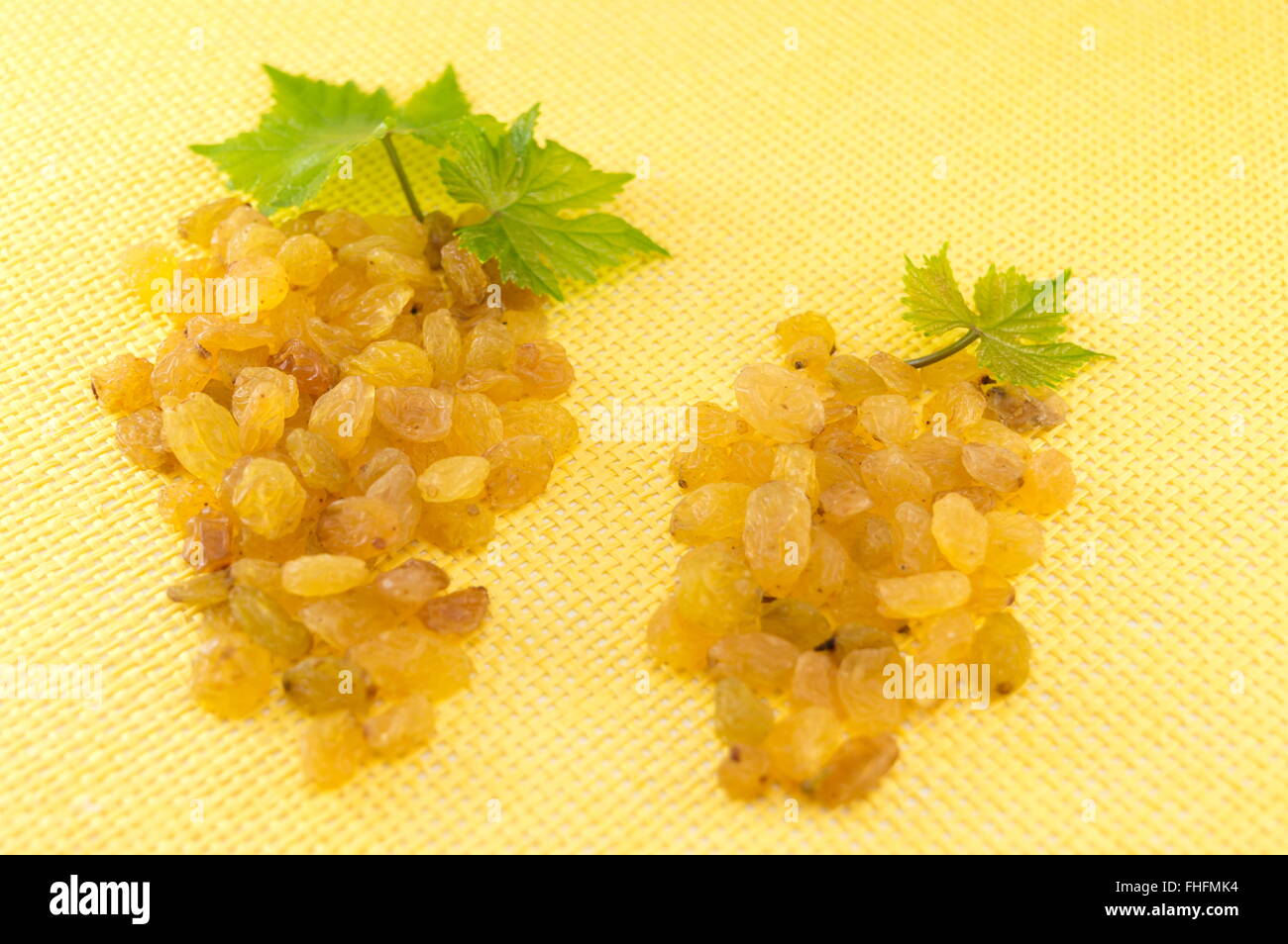 Uvetta formando un grappolo d'uva su sfondo giallo Foto Stock