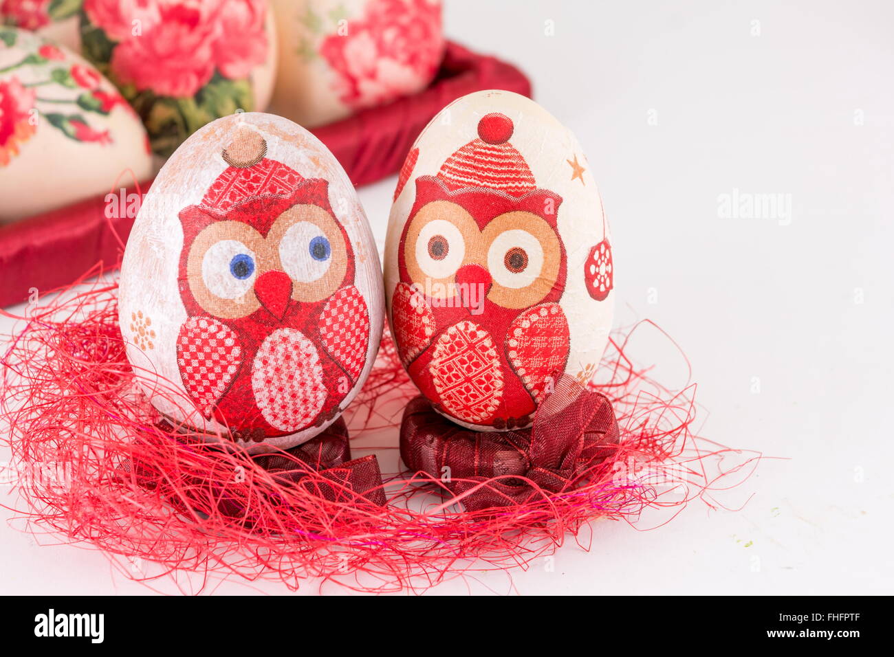 Paio di decoupage decorato uovo di Pasqua sulla paglia rosso Foto Stock