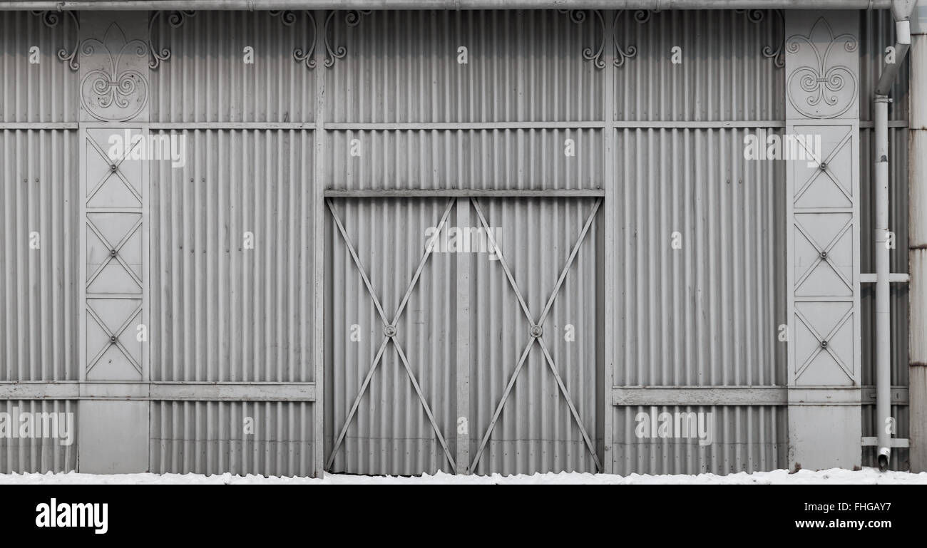Il vecchio edificio adibito allo stoccaggio muro fatto di rilievo dei pannelli di acciaio con gate Foto Stock