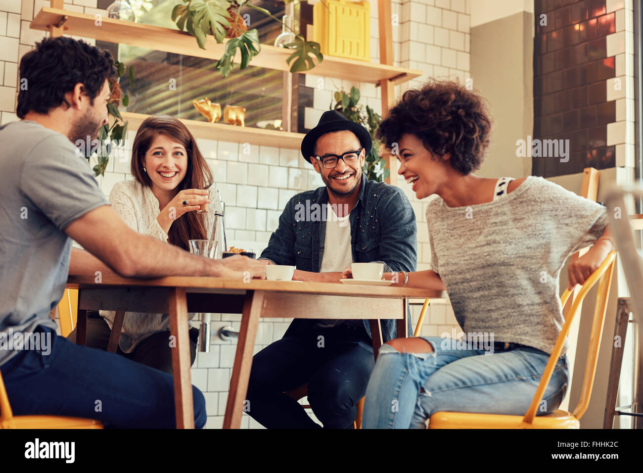 Ritratto di Allegro giovani amici divertendosi mentre si parla in una caffetteria. Un gruppo di giovani riuniti in un cafe'. Foto Stock
