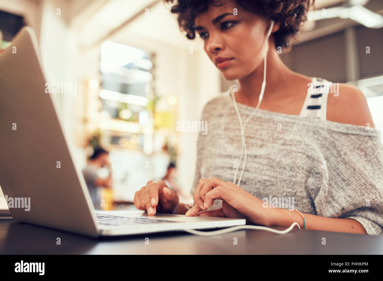 Ritratto di giovane donna alla ricerca occupato a lavorare sul computer portatile in un cafe'. Donna africana in seduta coffee shop utilizzando laptop. Foto Stock