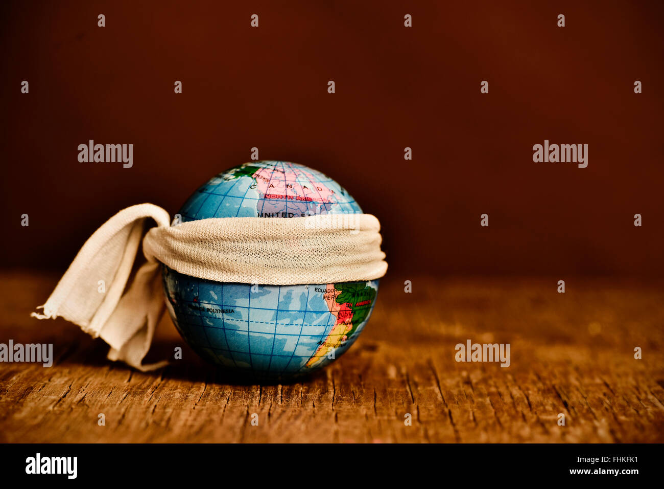 Un pezzo di stoffa legata intorno a un globo terrestre, posto su un rustico di una superficie di legno, con un effetto drammatico Foto Stock