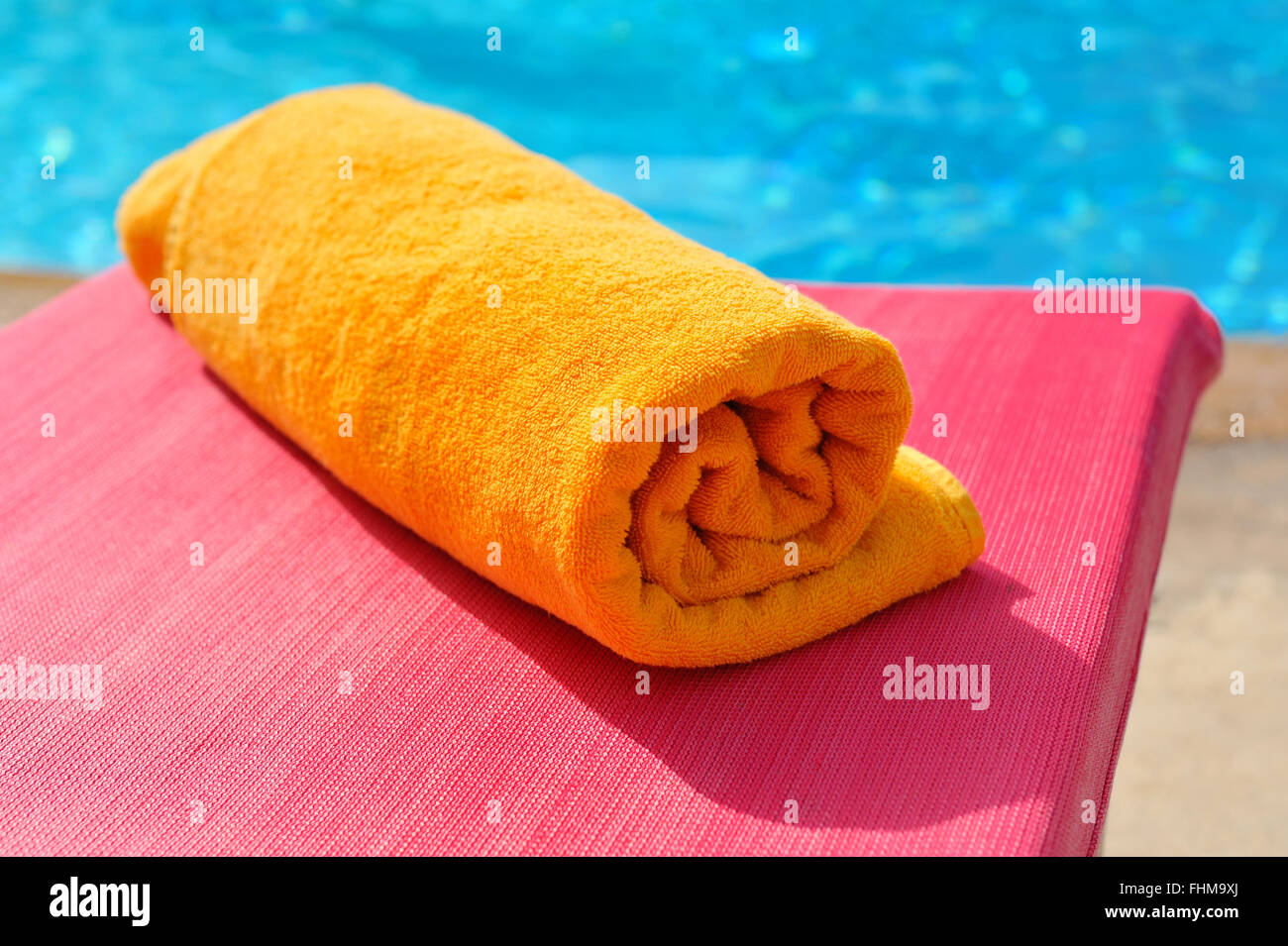 Ripiegata asciugamano arancione sullo sfondo della piscina Foto Stock